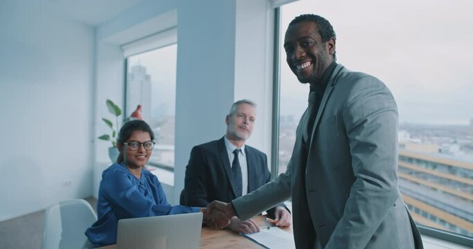 African candidate shake hands with recruiter and smile to the camera 