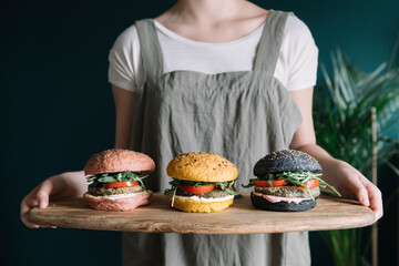 Young Woman Holding Three Colorful Vegan Burgers