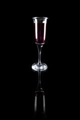 Transparent goblet with red wine on black reflective surface
