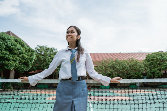 Beautiful A Girl Indonesian High School Student Standing Close At The Tennis Net With Sky And School Building Background