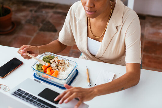 Crop black businesswoman using laptop during lunch