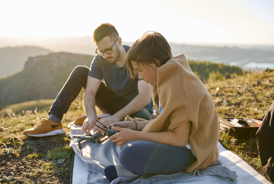 father and son fly and shoot video on a quadrocopter over the mountains at sunset