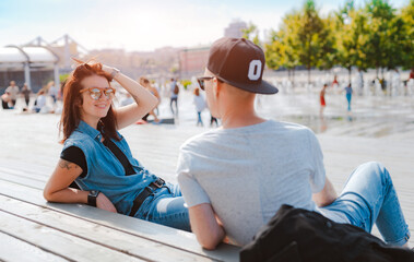 stylish young couple has fun chatting in a city park in the summer at sunset. A girl laughs at a date meeting with a boy friend