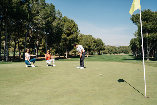 Man playing golf near women