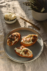 Bruschettas or toasts with cheese and fried mushrooms with thyme on greige linen tablecloth