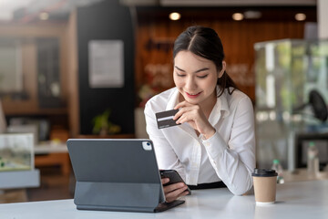 Young Asian businesswoman enjoy shopping online using credit card at a coffee shop.
