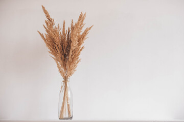 Still life of a bouquet of dried flowers in a glass bottle on a wooden table. Place for text or...