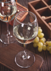 Glasses of white grape wine with grapes and wooden box on the background