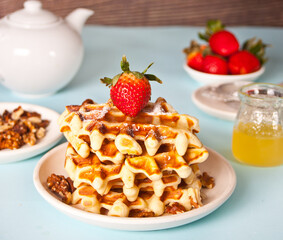 Freshly homemade baked waffles with strawberries and honey.