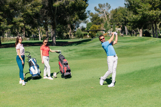 Man playing golf near women