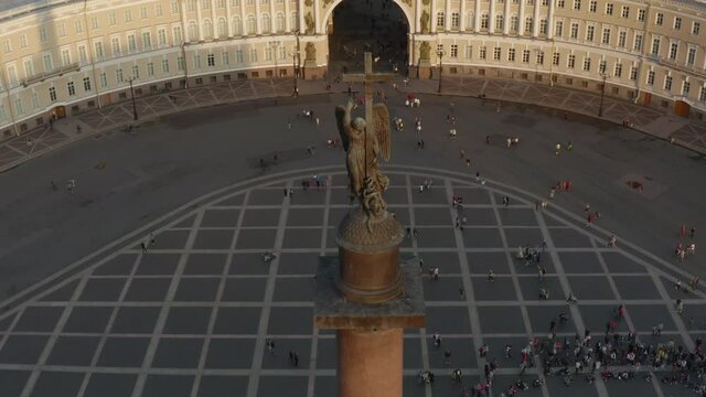 Aerial view of Palace Square and Alexander Column at sunset, The angel on a clone rises up, The drone falls downthe Winter Palace, the Hermitage, triumphal chariot, little people walks, 