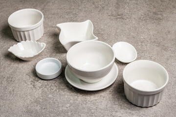 Fototapeta na wymiar Assorted white empty bowls and plates on a stone background
