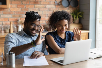 Friendly young afro american married couple contact lawyer consultant by video call using laptop...