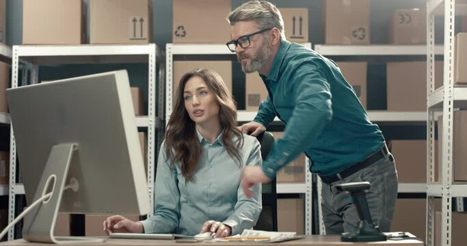 Senior director of warehouse checks work of managers and helps with advice to colleague. Female manager working with documents on computer.