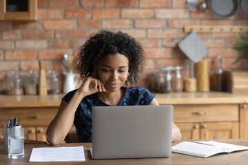Self employed businesswoman. Skilled confident black woman freelancer sit by laptop at home office...