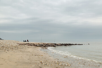 Pêcheurs avec leurs canne à pêches au bord de la mer en Normandie
