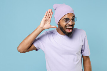 Young curious nosy student black african man 20s wearing violet t-shirt purprle hat glasses trying...