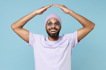 Young smiling happy positive unshaven black african man 20s in violet t-shirt hat glasses holding...