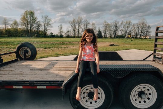 Girl sitting on trailer pouting.