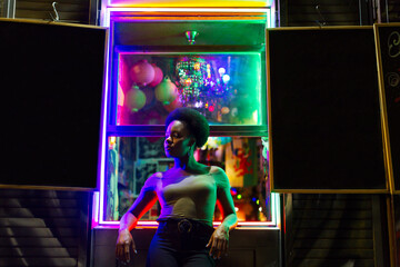 Attractive black woman leaning on windowsill of bar at night