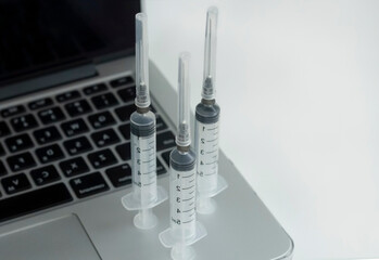 Syringes on a laptop on white background. Top view.