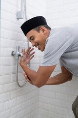 portrait of young Muslim man perform ablution (wudhu) before prayer at home. clean his hand