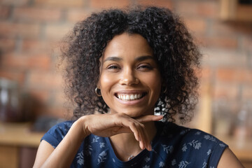 Headshot portrait of happy joyful young african american female show beautiful teeth in white cheerful smile. Adorable laughing millennial black woman looking at camera flirtatiously touching chin - Powered by Adobe