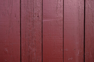 Weathered wooden boards on the wall of an old house. Paint texture. Burgundy color. Copy space. 