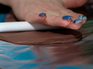 rolling out the polymer clay on the table. a woman's hand.
