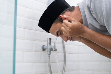 portrait of young Muslim man perform ablution (wudhu) before prayer at home
