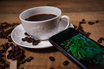 ブラックコーヒーとスマートフォンに写るコーヒーの木の画像