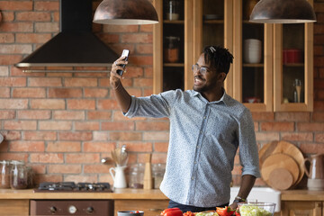 My culinary feats. Overjoyed afro caribbean male hipster shoot selfie on phone at home kitchen to...
