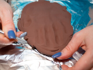 a cast of the boy's hand on polymer clay. cutting out the finished print