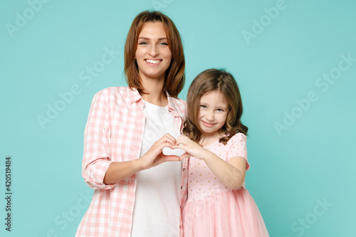 Happy woman in pink clothes have fun child baby girl 5-6 years old. Mommy little kid daughter showing shape heart with hands isolated on pastel blue background studio Mother's Day love family concept