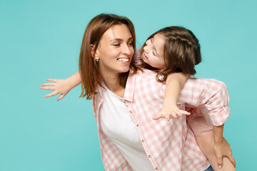 Happy woman in pink clothes have fun with child baby girl 5-6 years old Mommy little kid daughter stand behind hug kiss isolated on pastel blue azure background studio Mothers Day love family concept