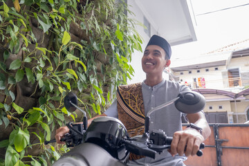 portrait of young muslim male going to the mosque by riding motorbike