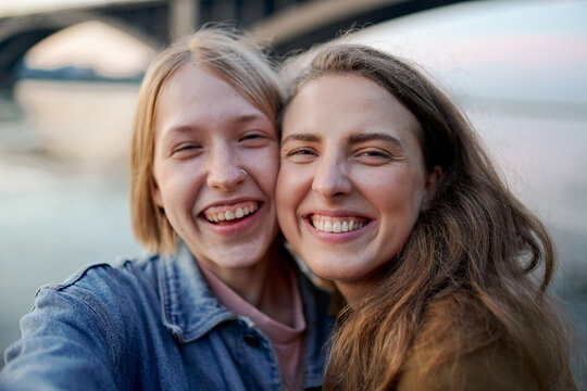 two girls take selfies on their smartphone while traveling