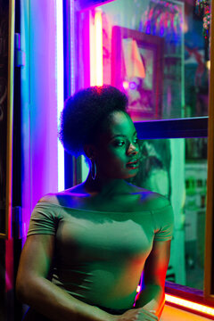 Portrait of Woman in profile leaning on a windowsill on neon lights