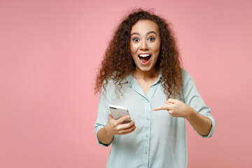 Young black african american surprised curly woman 20s wearing casual blue shirt point index finger...