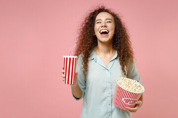 Young black african american laughing fun happy curly woman 20s in blue shirt holding popcorn...