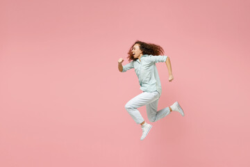 Fototapeta na wymiar Full length side view young black african fun happy smiling energetic sporty excited woman 20s in blue shirt jump high running fast hurrying up isolated on pastel pink color background studio portrait