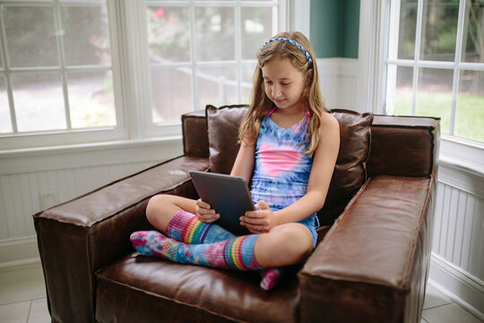Beautiful young girl in a tie dye shirt and socks using a tablet