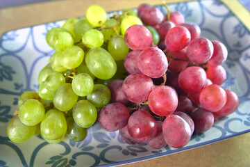 Bunches of white and red grapes on a white and blue tray.