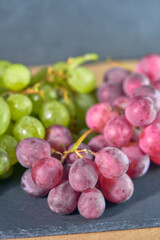 Bunches of white and red grapes on dark slate