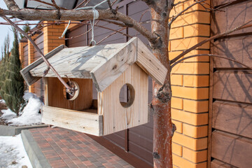 wooden house feeder for birds on branches