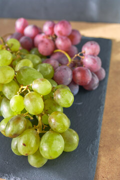 Bunches of white and red grapes on dark slate