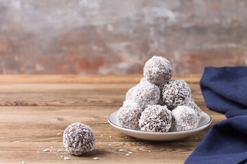 Coconut energy balls on a wooden tray, on a wooden table. Blurred background.