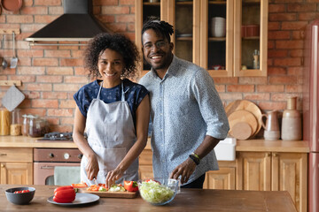Making healthy food choice. Family portrait of loving young afro american spouses cook easy...