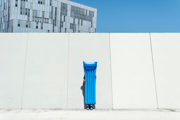 man hiding behind an air mattress outdoors