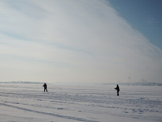Active elder people cross-country skiing on huge frozen lake during lovely winter sunset